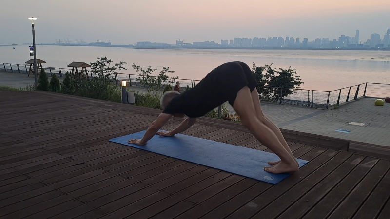A man doing yoga on the beach sidee.